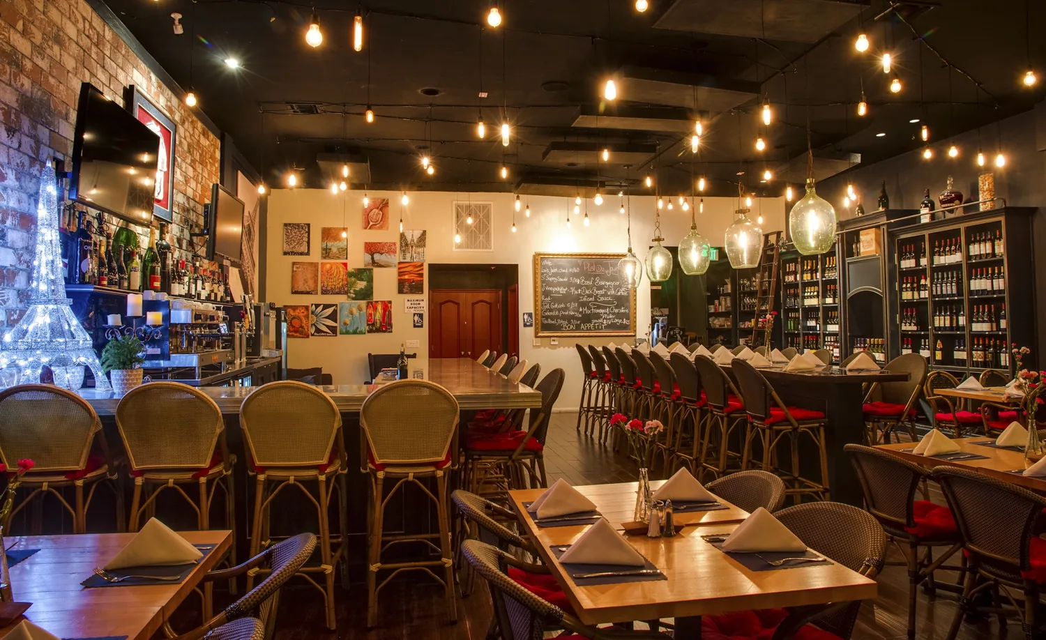 Bistro St. Germain dining room with a floor-to-ceiling wine wall and long communal table